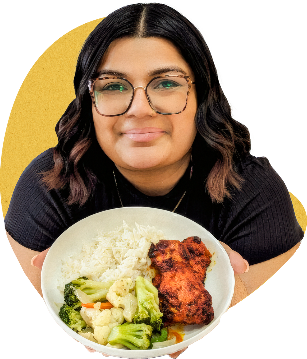 Juhi holding a bowl of butter chicken with rice and vegetables